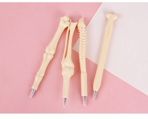 Close-up of four bone-shaped ballpoint pens in beige plastic with various skeletal designs