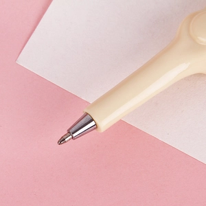 Novelty bone-shaped ballpoint pen in beige with metal nib writing on white paper