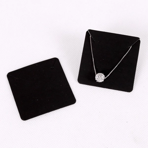 Black necklace display card with silver rhinestone ball pendant on white background