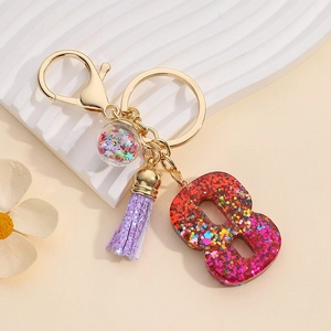 Detail of resin number 8 keychain with colorful sequins, gold ring and purple tassel
