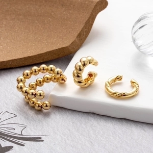 Detailed view of three gold-plated ear cuff designs featuring beaded and twisted textures