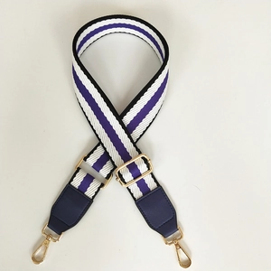 Detail of adjustable purple and black striped canvas strap with golden metal hardware