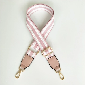 Detail view of adjustable pink and white striped bag strap with gold metal hooks