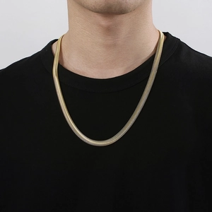 Macro shot of wide gold snake chain necklace featuring polished flat herringbone links