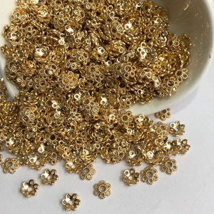 Detailed view of bulk golden flower-shaped metal bead caps for DIY jewelry making