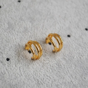 Vista macro di orecchini minimalisti a tre cerchi in ottone placcato oro da donna