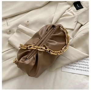Close-up of brown ruched cloud bag featuring chunky gold chain and leather texture