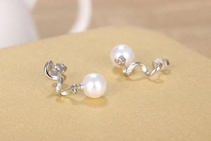 Close-up of elegant long pearl earrings with silver S-shaped curves and pavé zircon details