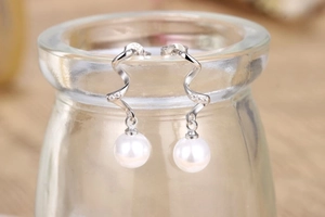 Macro shot of S925 silver spiral earrings with round white pearls and diamond accents