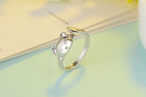 Close-up of cute silver cat open ring with delicate crystal eyes on a soft background