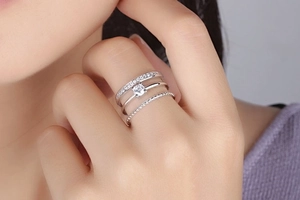 Detailed view of triple-layered silver ring with round-cut diamonds on model's finger