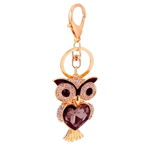 Gold owl keychain with sparkling rhinestones and dark crystals on a white background