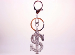 Detailed close-up of a silver dollar sign keychain with sparkling diamond accents