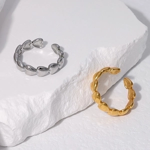 Detail of silver and gold heart-shaped chain link adjustable rings on white stone base