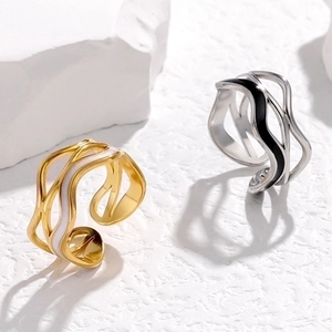 Close-up of wavy irregular steel rings with white and black enamel on stone