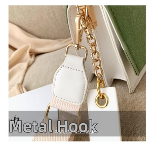 Detailed close-up of gold chain link and lobster clasp on a green and white handbag