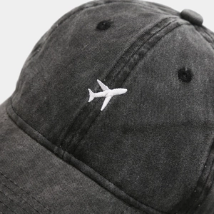 Washed charcoal baseball cap with white airplane embroidery in a minimalist vintage style