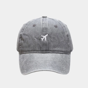 Detailed close-up of white airplane embroidery on a vintage grey washed cotton baseball cap