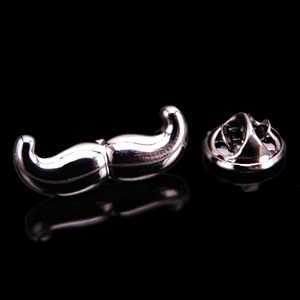 Polished silver mustache brooch pin with butterfly clasp on reflective black surface