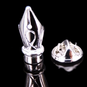 Macro shot of silver-tone fountain pen nib brooch with polished finish and butterfly clutch