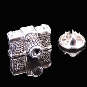 Macro shot of silver retro camera brooch with textured metal and butterfly clutch