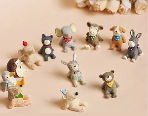Group shot of 11 assorted mini resin animal figurines on a soft pink background
