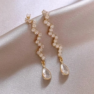 Elegant long gold drop earrings with wavy white zircon stones and teardrop crystal pendant