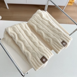 Minimalist cream cable knit wool warm socks with branded fabric label on a white tray