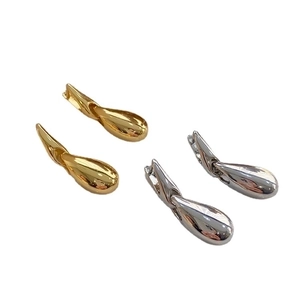 Minimalist gold and silver teardrop earrings with a polished metallic finish on white back