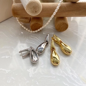 Polished gold and silver teardrop hoop earrings displayed with elegant pearl necklace