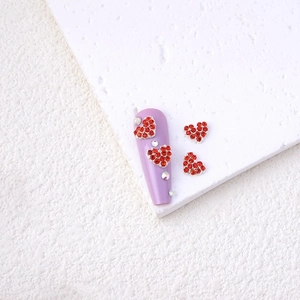 Macro shot of alloy heart rhinestones and clear crystals on purple nail tips