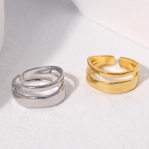 Detail of minimalist gold and silver double-layered open rings with smooth metallic texture