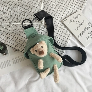 Détail d'un sac bandoulière en toile vert menthe orné d'un mignon petit ours en peluche beige