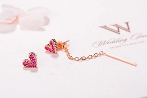 Macro detail of rose gold heart earrings with pink zircons on brand jewelry card