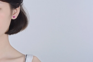 Close-up of elegant rose red heart stud earring worn on model's ear for daily style