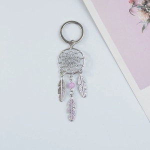 Detail of a silver dreamcatcher keychain with metallic feathers and a purple bead