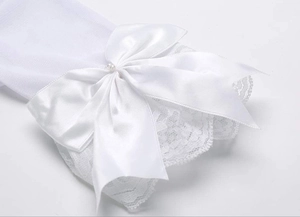 Detail of white bridal lace gloves featuring a satin bow and central pearl embellishment