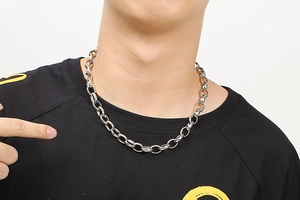 Macro view of silver stainless steel cable chain necklace on a black crew neck shirt