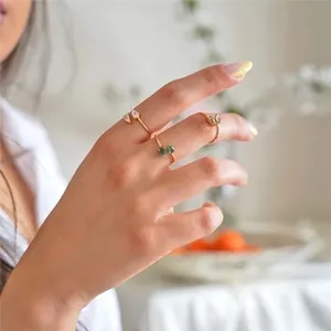 Detail of stacked gold rings featuring teardrop crystals in pink, green, and clear