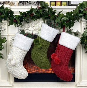 Trois chaussettes de Noël en tricot colorées suspendues sur un manteau de cheminée blanc