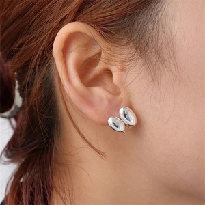 Minimalist silver pebble earrings with polished finish shown on model's ear
