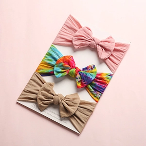 Detailed view of three embroidery cotton bow headbands in pink, tie-dye, and khaki colors