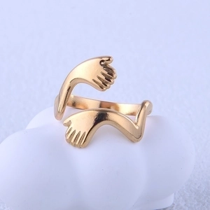Detailed macro view of a gold hugging hands stainless steel ring on a white decor