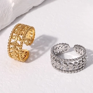 Detail of 18K gold and silver leaf rings on white rock, showing hollow design and texture