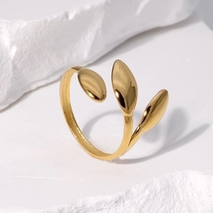 Minimalist gold leaf stainless steel open ring displayed on white textured stone background