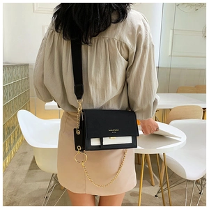 Detail of a black and white PU leather crossbody bag with a gold chain on a model