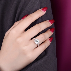 Macro shot of 1 carat round halo moissanite ring on model hand with silver band
