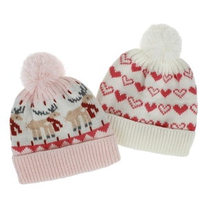 Close-up of pink reindeer and white heart patterns on soft knit beanies with fluffy pom-poms