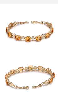 Detail of golden bracelet featuring oval yellow gemstone and floral clover links