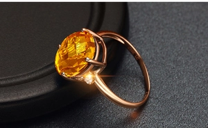 Macro shot of 18K rose gold ring featuring a cushion-cut yellow gemstone and side diamond